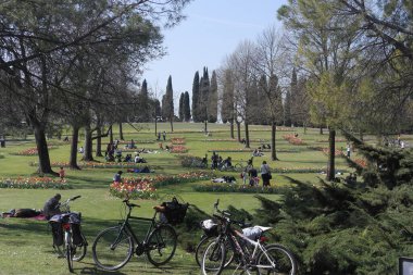 İtalya Sigurta bahar parkında dinlenme zamanı siesta, yeşil çimenli çayırlarda bisikletler lale yatakları, selvi ağaçları. İtalya 'da tatil deneyimi