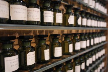 Antique opaque glass ingredient bottles (via, flacon,containers) on shelves with essence extract substances,to mix fragrances, making french aroma perfumery. Fragonard Museum. Paris inspiration history of perfume manufacturing.