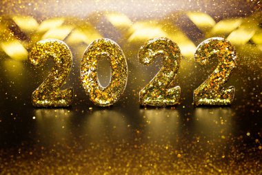 Tatil geçmişi 2022 Yeni Yıl. Altın 2022 numaralı ışıltılı noel, siyah desenli arka planda bulanık bokex ile parıldıyor. Şenlik konsepti. Doku Altın Parıltısı.