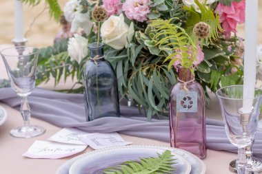 Renkli çiçeklerle, çatal bıçaklarla, mumlarla süslü bir masa. Düğün masası dekorasyonu. Şenlikli akşam yemeği için masa dekorasyonu.