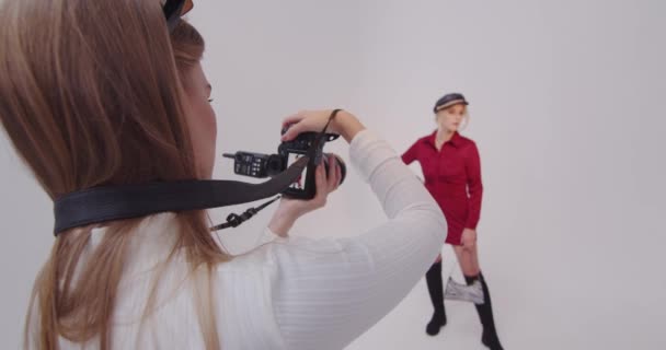 Flicka fotograf gör skott med en modell i en fotostudio — Stockvideo