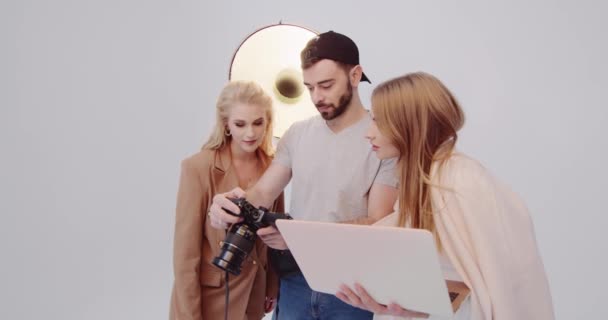 Stylista s fotografem a modelkou si vybírají záběry z focení — Stock video