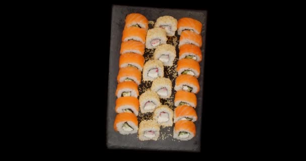 Sushi feküdt egy tányéron, készen áll az evésre, fekete háttér — Stock videók