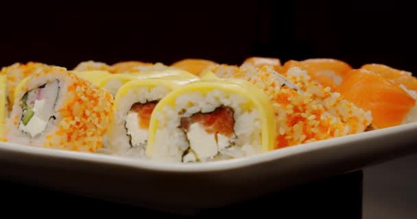Sushi colocado em um prato, pronto para comer, fundo preto — Vídeo de Stock