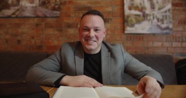 Gülümseyen adam dizüstü bilgisayarla bir konferans düzenliyor ve ekrana bakıyor.