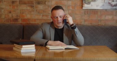 Ciddi bir ifadesi olan bir adam kitap okur ve çağrıya cevap verir.. 