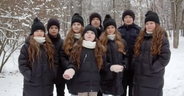 Kinderen verzameld voor een wandeling in een besneeuwd park — Stockvideo