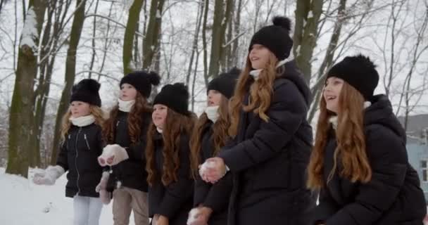 Viele fröhliche Kinder genießen den Schnee, Mädchen formen und werfen Schneebälle — Stockvideo