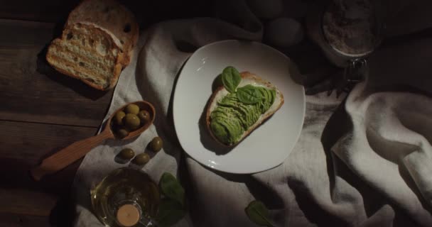 Sandwich apetitoso con aguacate y espinacas, colocado sobre una mesa de madera cubierta — Vídeos de Stock