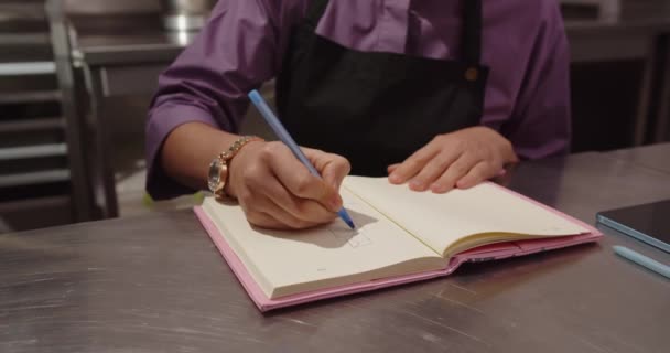 Кондитерська дівчина малює ескізи тортового зошита, сидячи в кондитерському магазині — стокове відео
