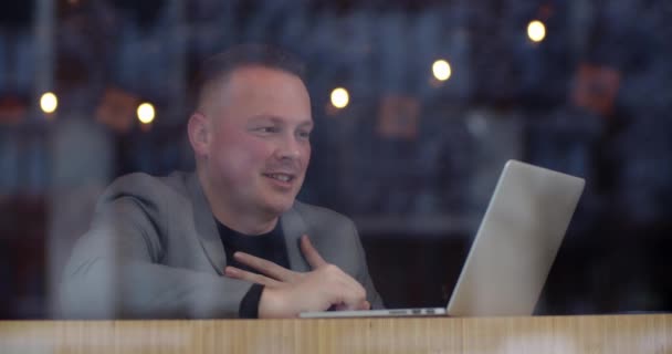 Чоловік сидить у кафе і розмовляє на відео через ноутбук — стокове відео