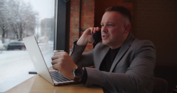 Muž, který sedí v kavárně a mluví po telefonu, rozhoduje o pracovních chvílích. — Stock video