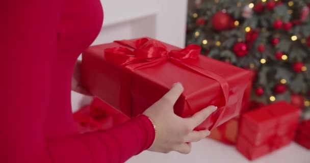 Rendezd el az ajándékokat a karácsonyfa alatt, a vörös ruhás lányt.. — Stock videók