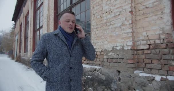 A man walks the old streets and talks on a cell phone — Stockvideo