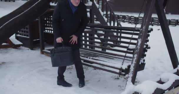 会議を待っている雪で覆われたスイングに座っているビジネスマン — ストック動画
