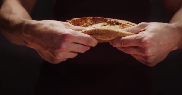 Ένας άντρας κόβει ένα καρβέλι φρεσκοψημένο ψωμί στη μέση. Σπιτικός φούρνος. — Αρχείο Βίντεο