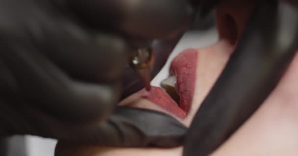 Permanente make-up. De master brengt rode verf aan op de lippen van de klant — Stockvideo