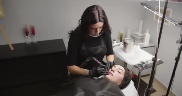 The Master In The Beauty Salon Uses A Special Device Apply Red Paint On The Lips — Stockvideo