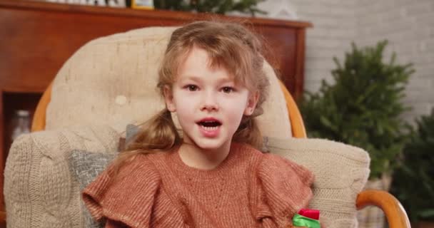 Niña sentada en un sillón y cantando una canción infantil — Vídeos de Stock