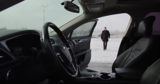 A man on a snowy street goes to his car — Stockvideo