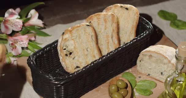 Put fresh toasters in a basket on a table decorated with a bouquet of flowers — Vídeo de Stock