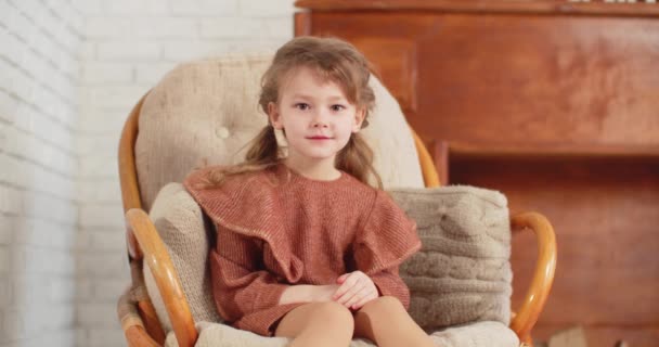 La chica está sentada en una silla y sonriendo — Vídeos de Stock