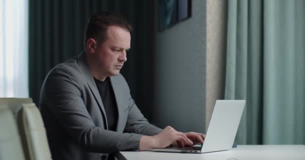 Чоловік у діловому костюмі працює онлайн на ноутбуці — стокове відео