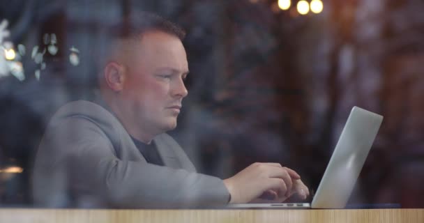Чоловік дивиться на екран ноутбука в приміщенні — стокове відео