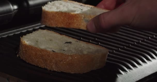 Put slices of fresh bread on the heated grill surface — Stockvideo