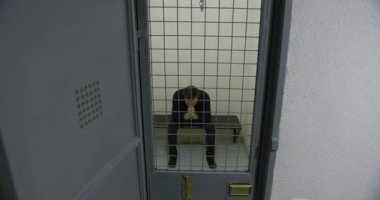 Hapishane hücresindeki parmaklıklar ardındaki adam. Suçlu.