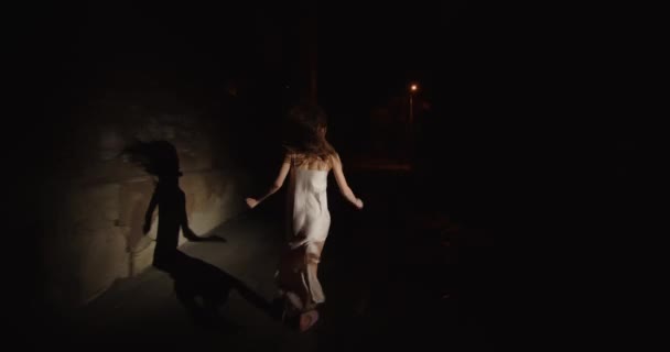 夜のガウンを着た怖い女が通りを走って家から逃げ出した. — ストック動画