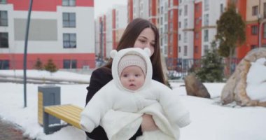 Neşeli anne kışın sokakta yürür, kucağında bir çocuk