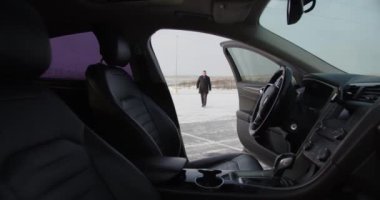 İşadamı, karlı bir caddedeki otoparkta arabasına gidiyor.