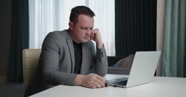 Arbeiten Sie online. Mann im Business-Anzug sitzt zu Hause am Computer — Stockvideo