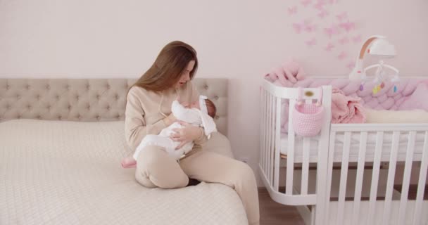 Joven madre arrulla bebé sosteniéndolo en sus brazos — Vídeos de Stock