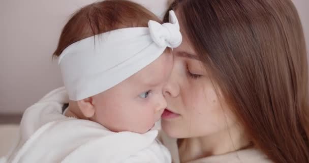 Una giovane madre tocca delicatamente il viso del suo neonato, tenendola tra le braccia. Amore materno — Video Stock