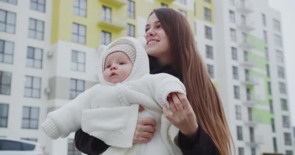 Alegre madre camina por la calle en invierno, sosteniendo a un niño — Vídeos de Stock