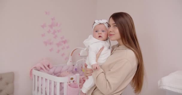 Glückliche junge Mutter mit einem Neugeborenen, das neben der Krippe steht — Stockvideo