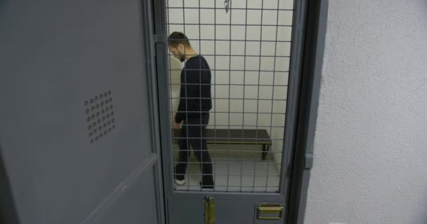 El hombre tras las rejas en una celda de prisión. El criminal — Vídeo de stock
