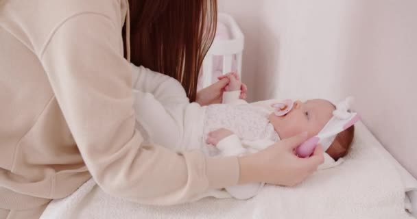 Zorgzame moeder kamt het haar van een pasgeboren meisje — Stockvideo