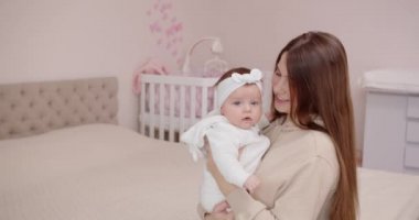 Mutlu bir genç anne, bebeğiyle oynuyor ve onu kollarına alıyor.