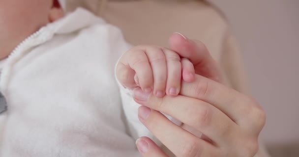 Egy újszülött kezében egy anya ujja a kis tollával. Anya gyengéden simogatja a pici tollat. — Stock videók