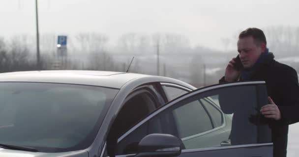 Бизнесмен разговаривает по телефону и открывает дверь машины — стоковое видео