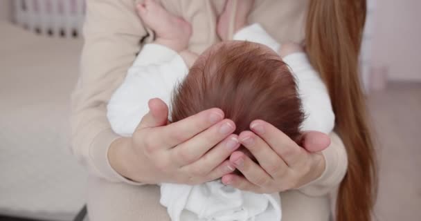 Genç bir anne yeni doğmuş bir bebeği kucağında tutar ve küçük kafasından destek olur. Anne bakımı. — Stok video