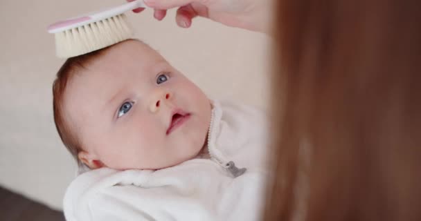 Η μαμά χτενίζει απαλά τα μαλλιά του νεογέννητου μωρού της. — Αρχείο Βίντεο