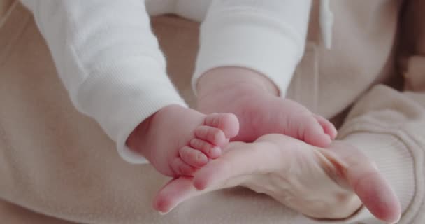 Материнская любовь. Заботливая мать держит детские ноги в руках — стоковое видео