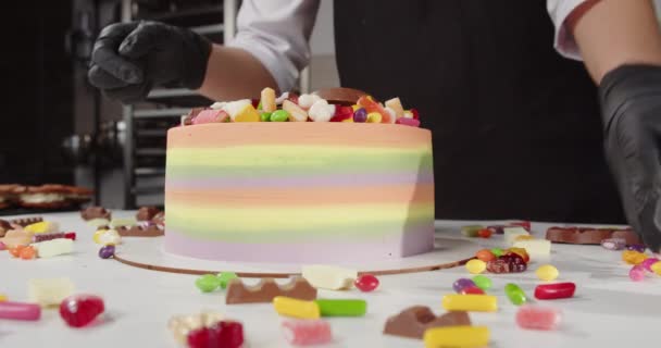 Кондитер украшает праздничный торт сладостями в кондитерской — стоковое видео