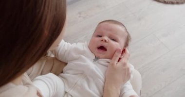 Genç bir anne yeni doğmuş bir bebeği kucağında tutar ve nazikçe yüzünü okşar. Anne bakımı.