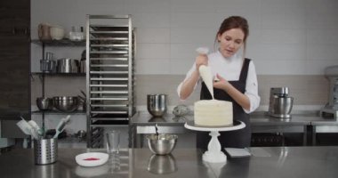 Pasta koluyla pasta şefi pastaya krema sürüyor.