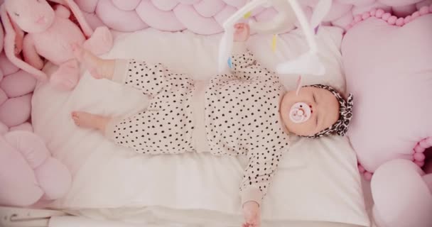小さな新生児の女の子はクレードルにあり、おもちゃを見て01 — ストック動画